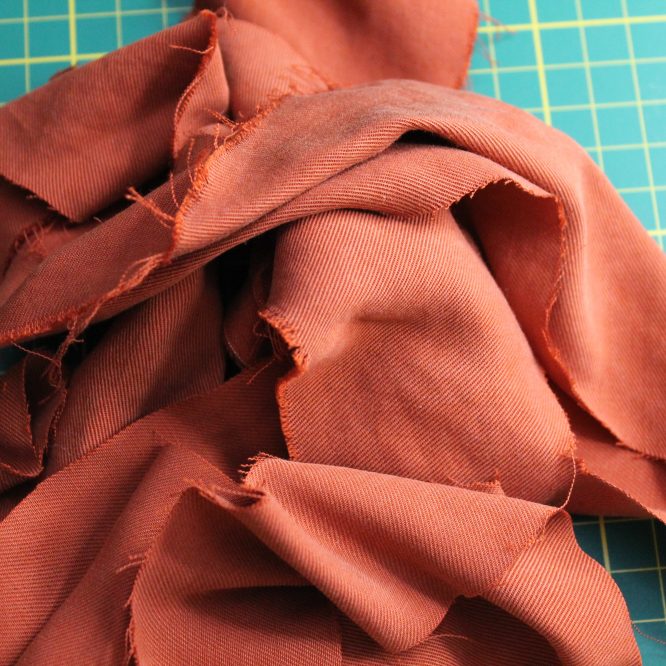 tas de chutes de tissus en Tencel sur une planche de découpe verte.